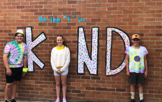 St John Bosco Catholic Primary School Engadine students standing in front of a 'Be the I in Kind' mural